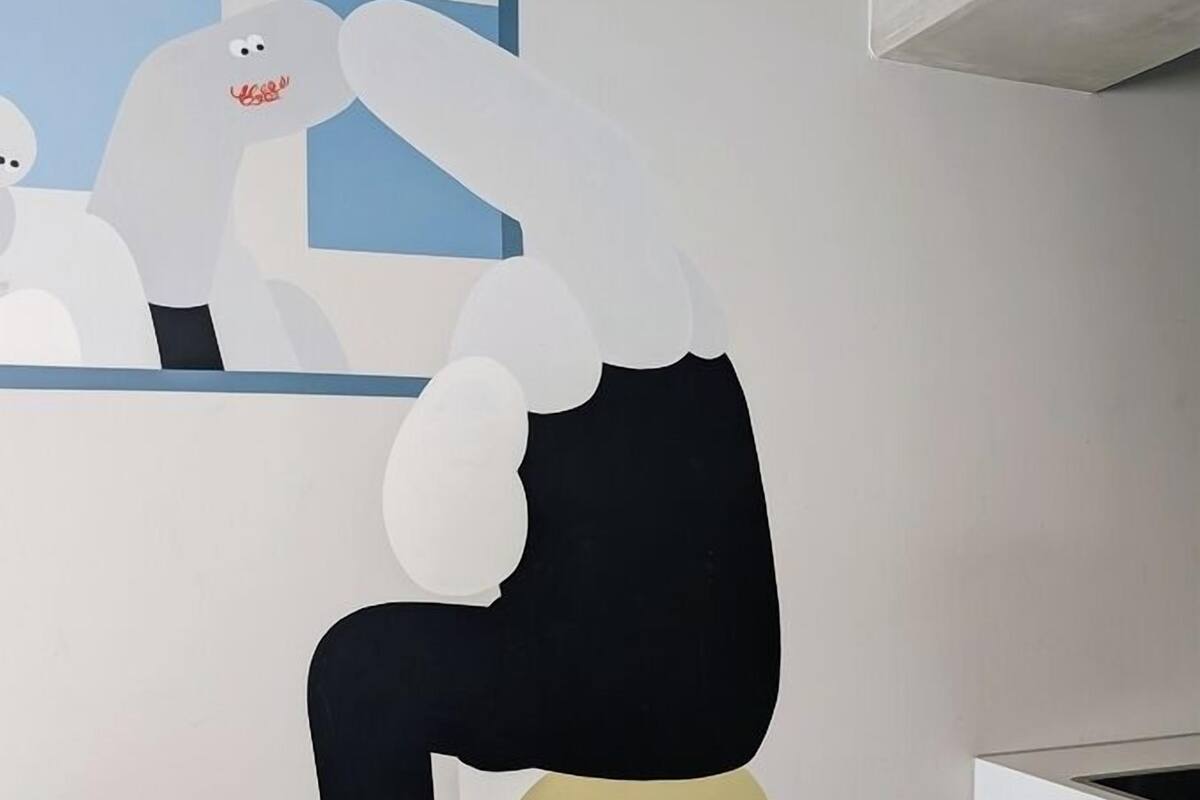 Un mur orné d’une grande fresque abstraite représentant une figure avec une tête blanche et un corps noir.