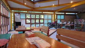 Amplia habitación con bancos de madera, una mesa con un paquete y una motocicleta al fondo.