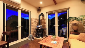A cozy living area with a fireplace, a wooden table, and a sofa. - Pension C-cabin (Minamiboso)