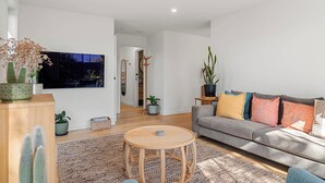 A modern living room with a sofa, a coffee table, and various plants. - Central and very close to retail hub, restaurants, cafes, Coles, Woolworths (Cowes)