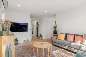 A modern living room with a sofa, a coffee table, and various plants. - Central and very close to retail hub, restaurants, cafes, Coles, Woolworths (Cowes)