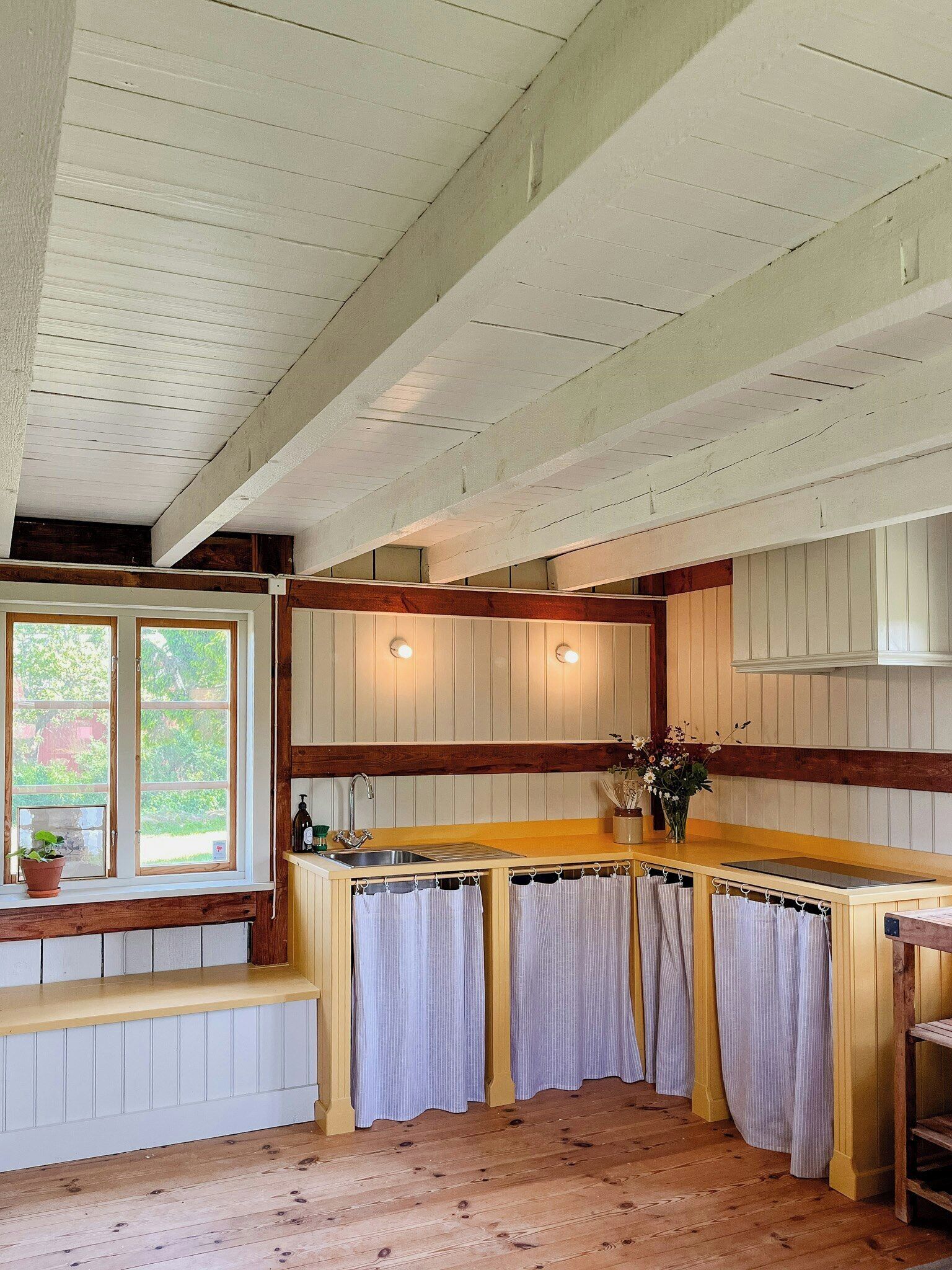 Una cocina con vigas de madera, un ventanal con vistas, un lavabo y una encimera.