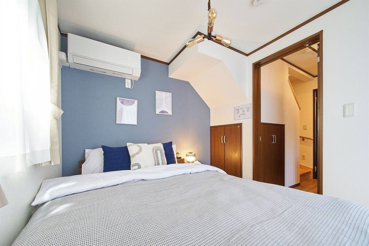 A bedroom with a bed, an air conditioning unit, a ceiling fan, and a wardrobe.