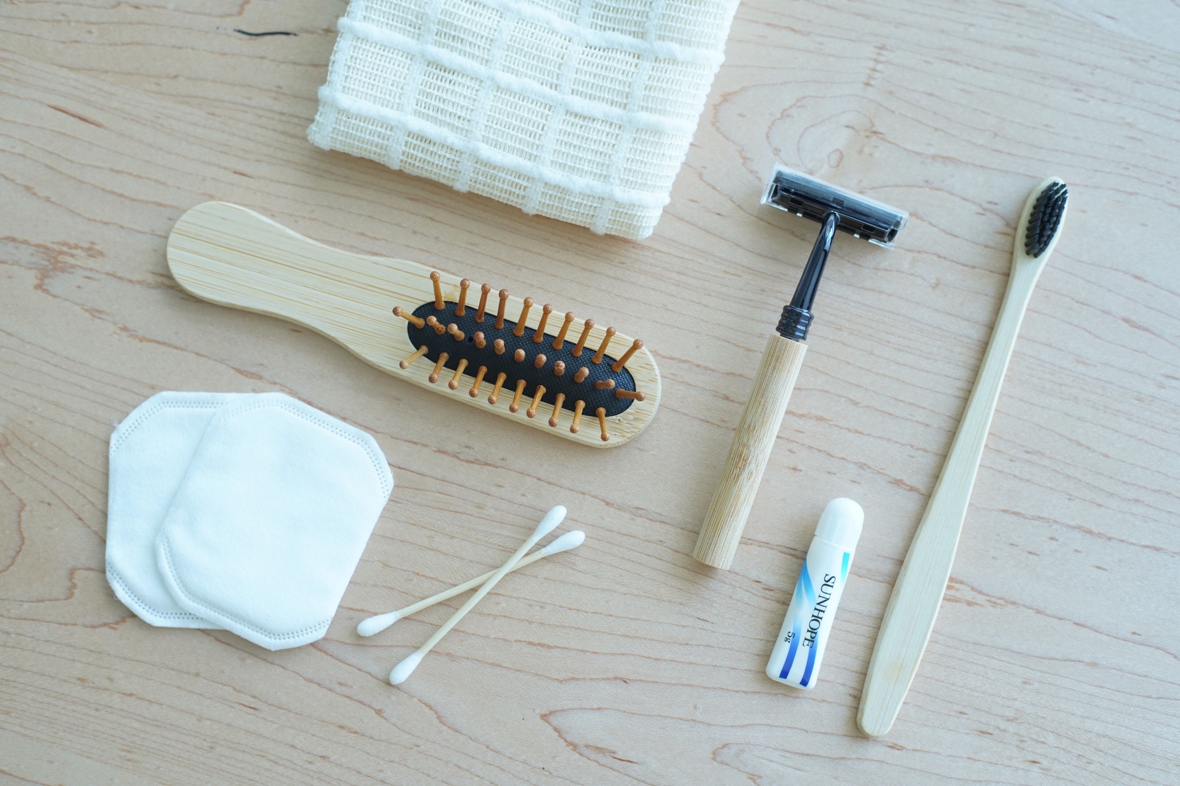 A wooden surface with a toothbrush, a comb, a razor, a face mask, and cotton swabs.