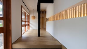 Un intérieur moderne avec un plancher en bois, une colonne noire et un luminaire tressé.
