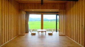 Une pièce en bois avec une grande fenêtre, deux chaises et une table.