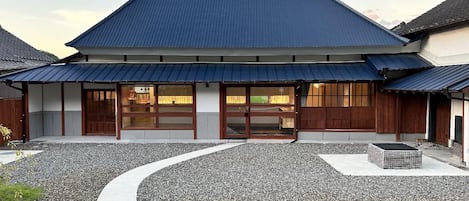 Un bâtiment traditionnel japonais, avec un chemin de gravier sinueux menant à l’entrée.