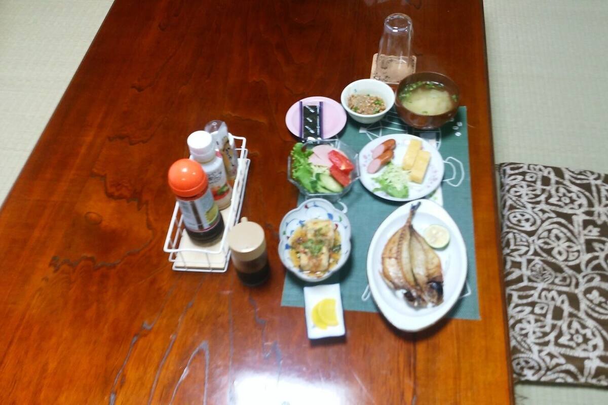 A wooden table with various dishes, condiments, and a glass bottle.