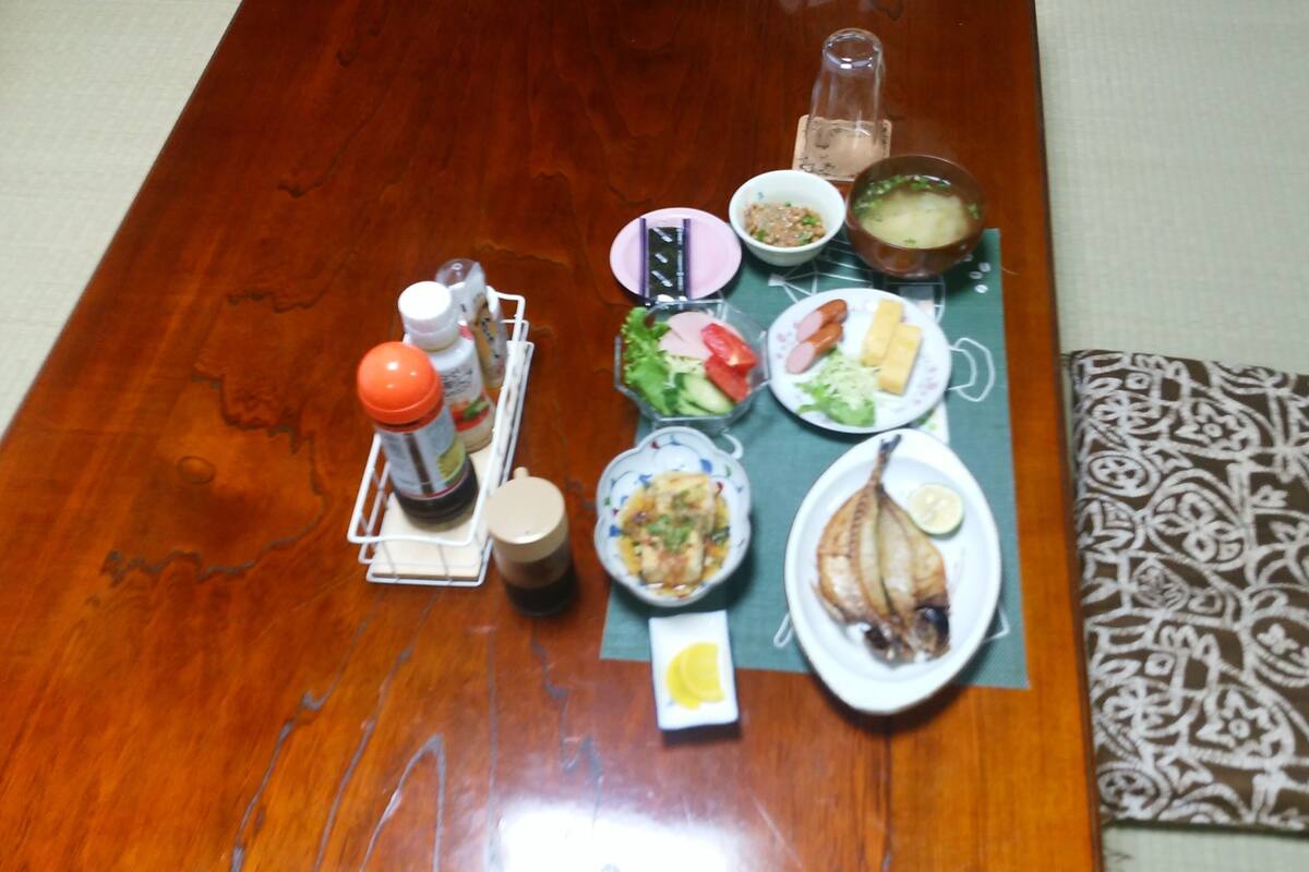 A wooden dining table with various dishes, condiments, and a bottle of water.