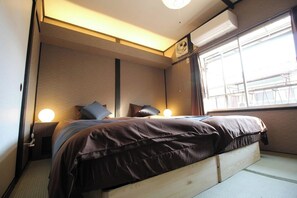 A bedroom with a bed, bedside lamps, a window, and an air conditioning unit. - Kyo-hiiragi (Kyoto)
