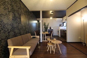 A modern living room with a sofa, a dining table with chairs, and a kitchen area in the background. - Kyo-hiiragi (Kyoto)