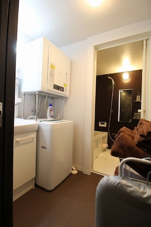 A compact bathroom with a washing machine, a shower, and a towel rack. - Kyo-hiiragi (Kyoto)