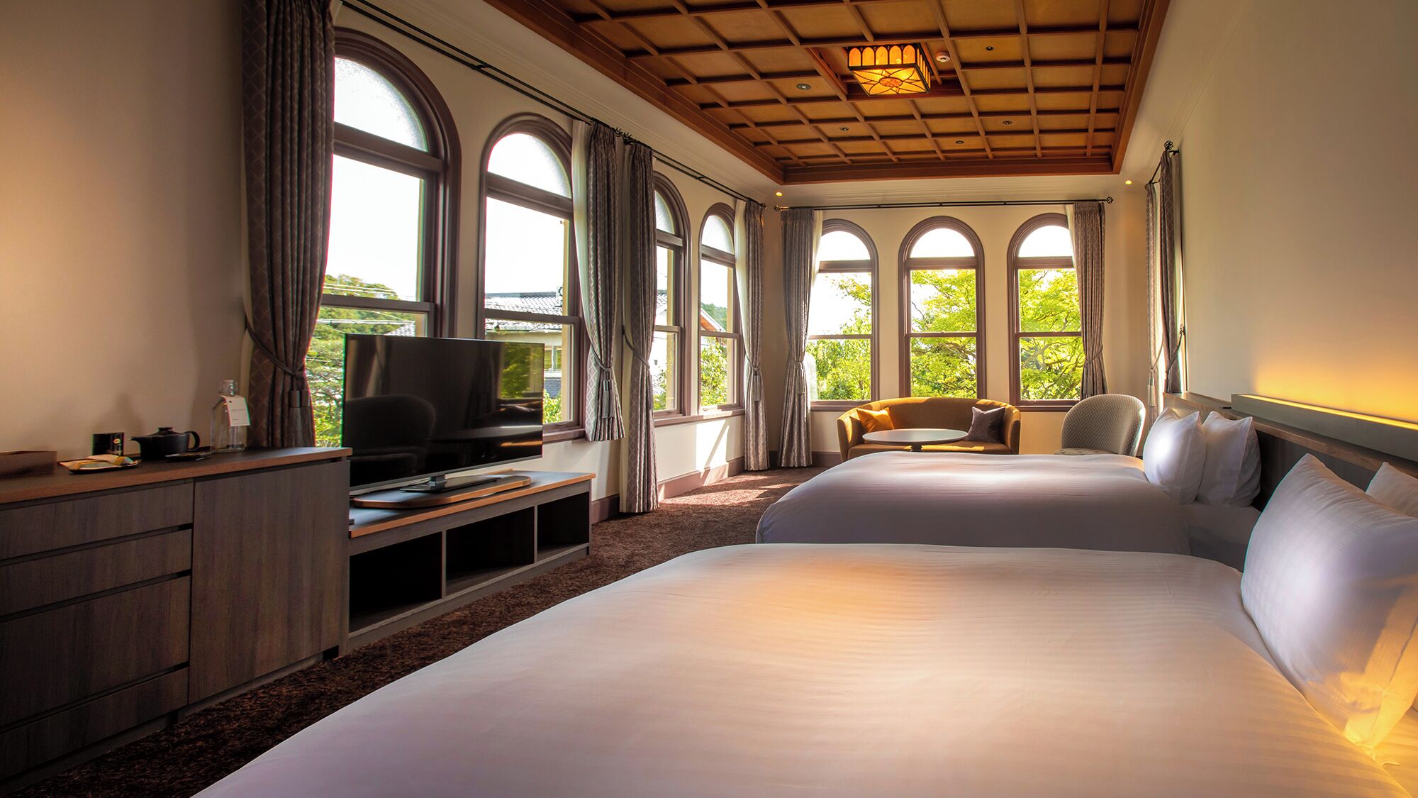 A hotel room with a large bed, a TV, a desk, and a sofa.