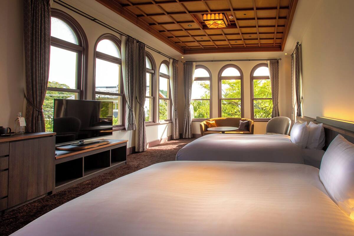 A hotel room with a large bed, a TV, a desk, and a sofa.