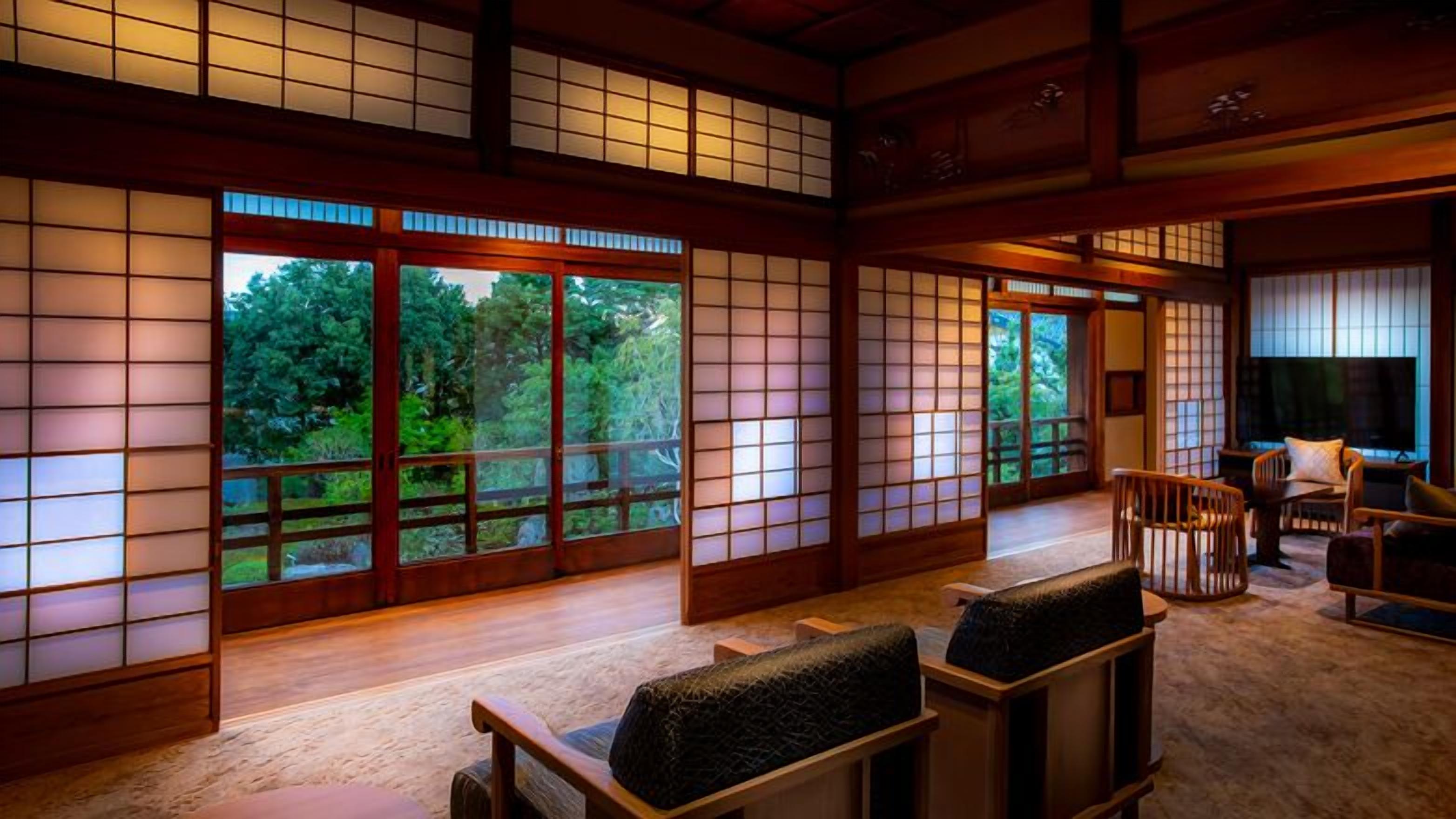 A traditional Japanese room with tatami flooring, sliding doors, and a view of greenery outside.