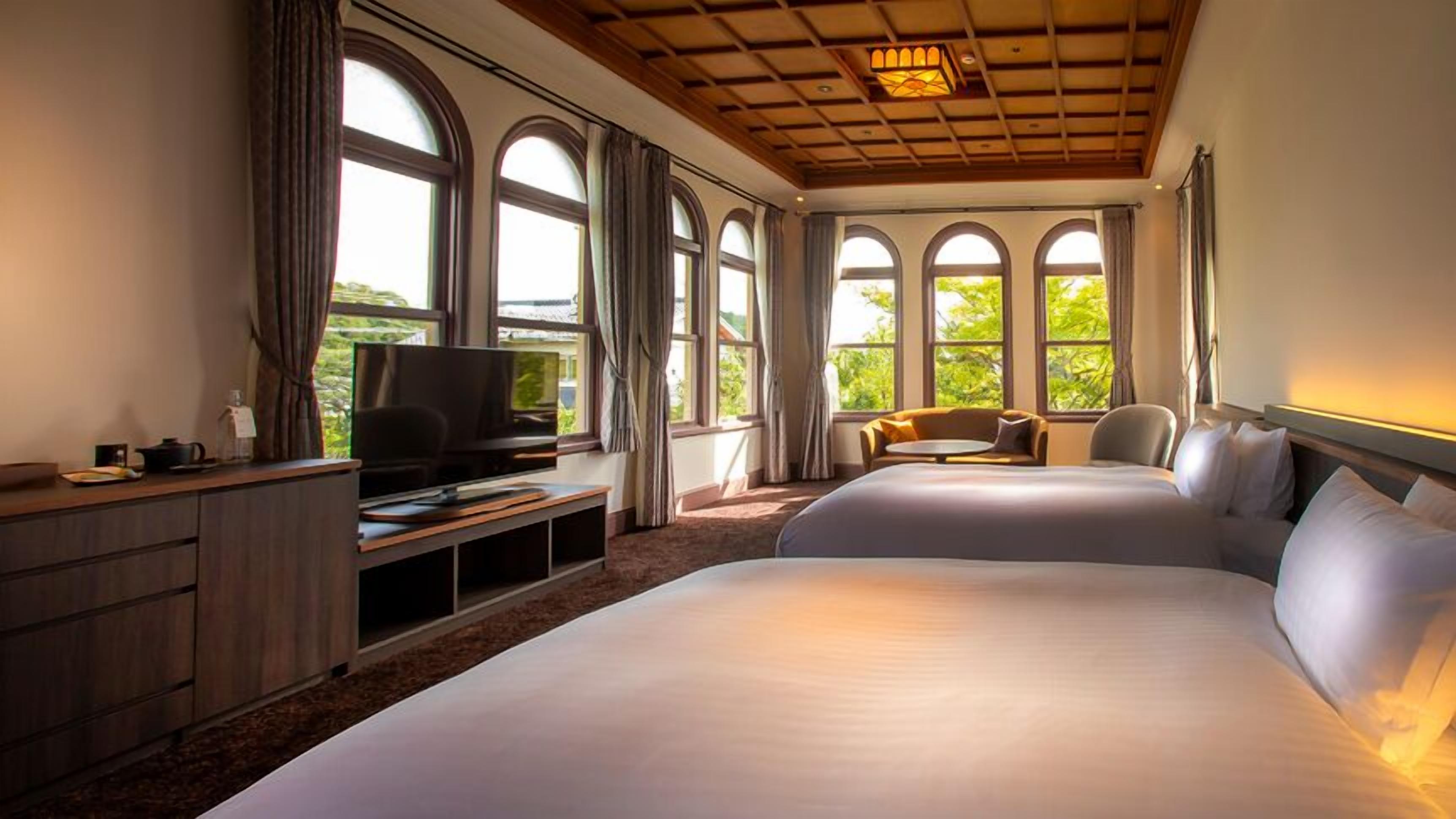 Habitación de hotel con una cama grande, televisión, escritorio y ventana con vista a zonas verdes.