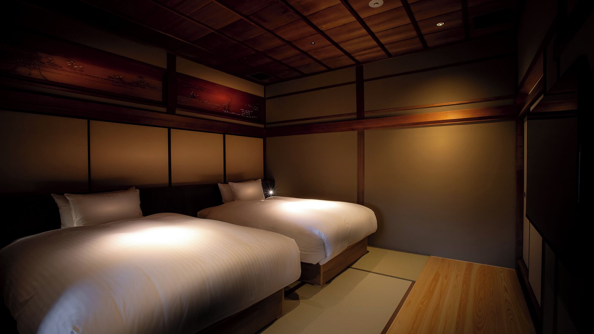 A room with two beds, wooden paneling, and a ceiling light.
