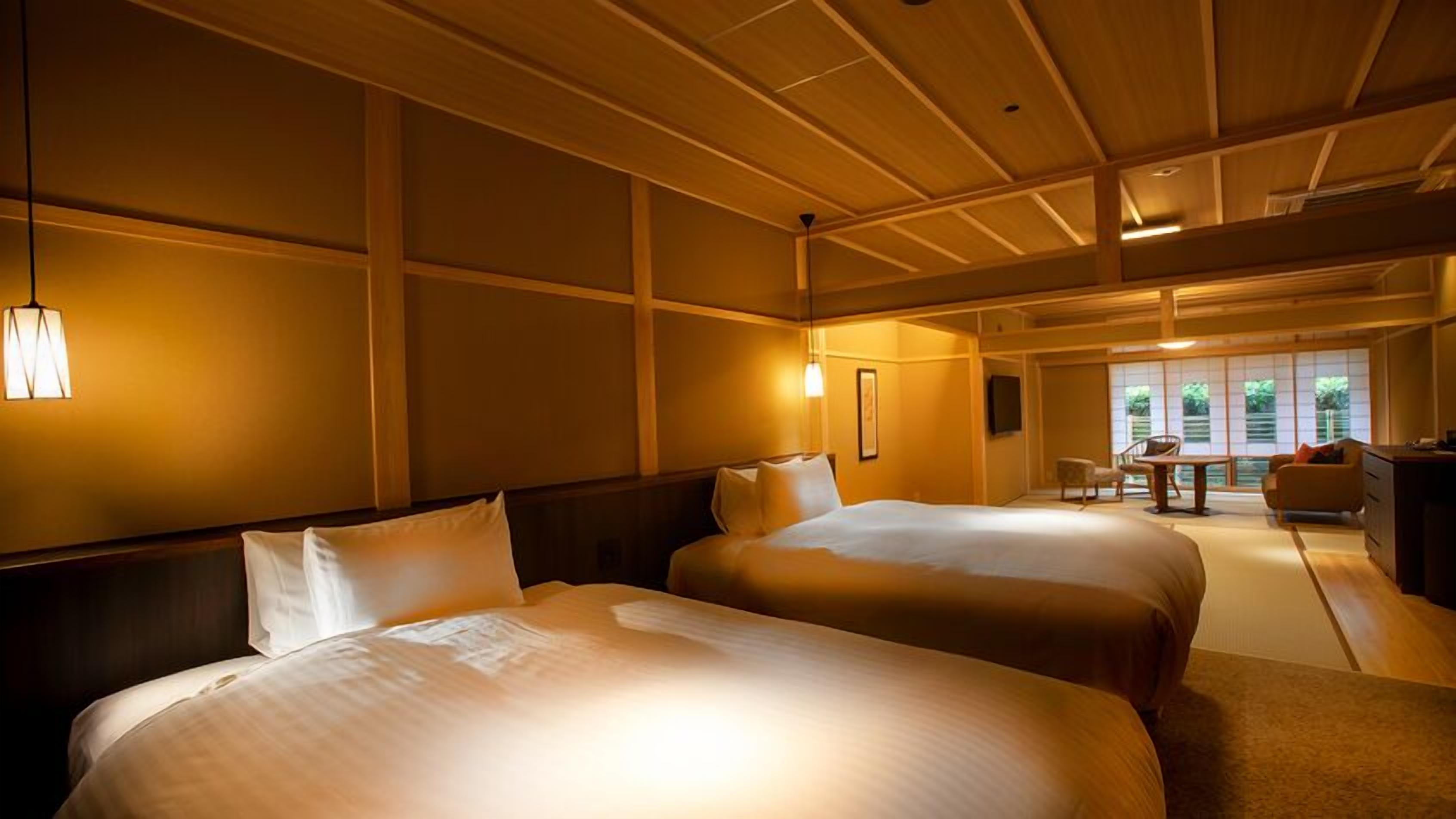 A hotel room with two beds, a desk, and a view of the outdoors.
