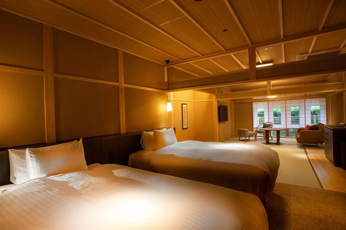 A hotel room with two beds, a desk, and a view of the outdoors.