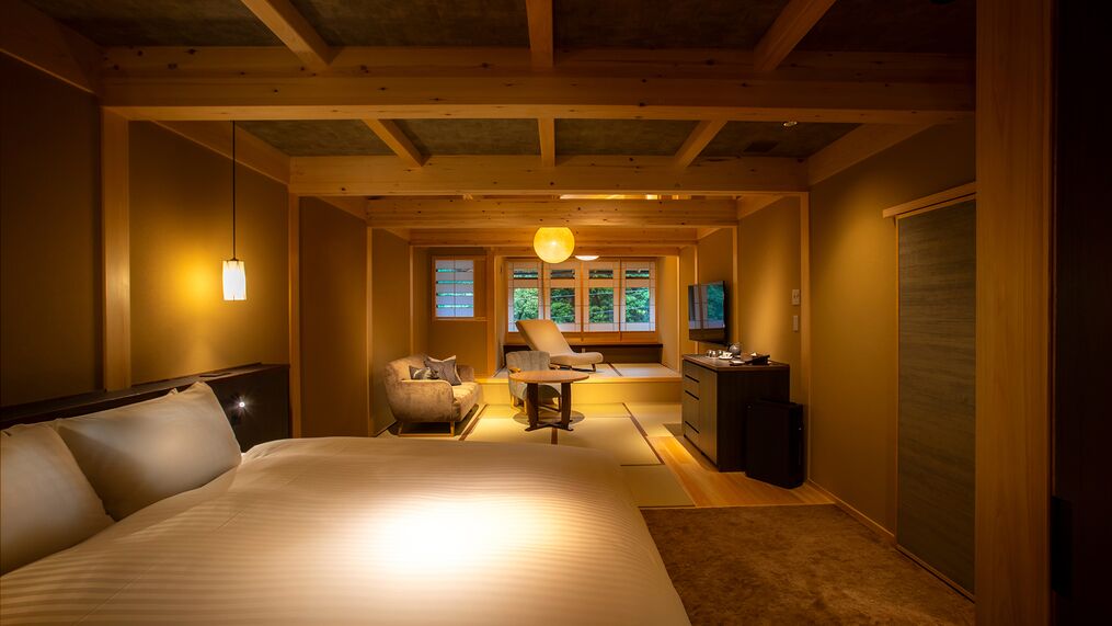 A bedroom with a large bed, a desk, a chair, and a television.