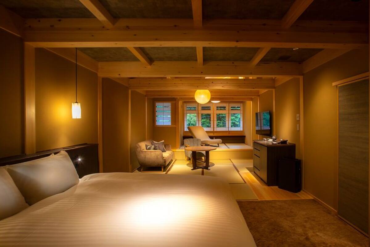 A bedroom with a large bed, a desk, a chair, and a television.