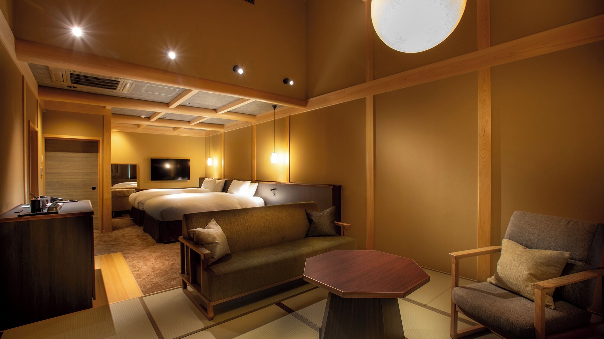 A hotel room with a large bed, a sofa, a small table, and a TV.