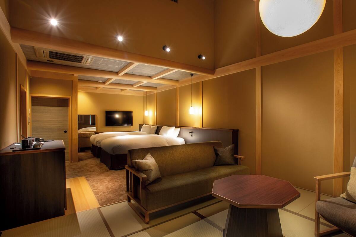 A hotel room with a large bed, a sofa, a small table, and a TV.