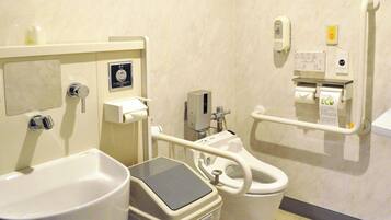 Un baño con inodoro, bidé, secamanos y dispensador de jabón.