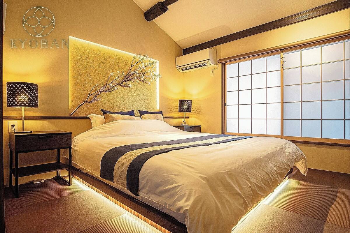 Une chambre d’hôtel avec un grand lit, un climatiseur fixé au mur, une fenêtre avec vue et un élément décoratif mural.