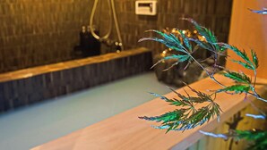 A bathroom with a wooden bench, a shower area, and a small plant on the counter. - Kyoran-ruantei (Kyoto)