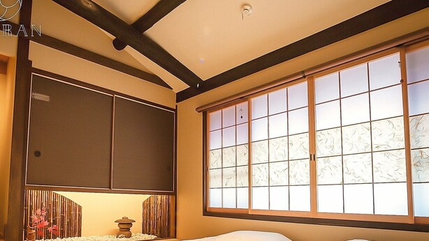 A traditional Japanese-style room with tatami flooring, a low bed, sliding doors, and a large window with a view. - Kyoran-ruantei (Kyoto)