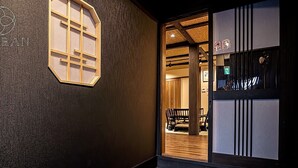 A dark interior hallway with a wooden door leading to a room with a bench and a small table. - Kyoran-ruantei (Kyoto)