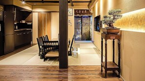 A hallway with a wooden floor, a dining area with chairs, a table, and a potted plant. - Kyoran-ruantei (Kyoto)