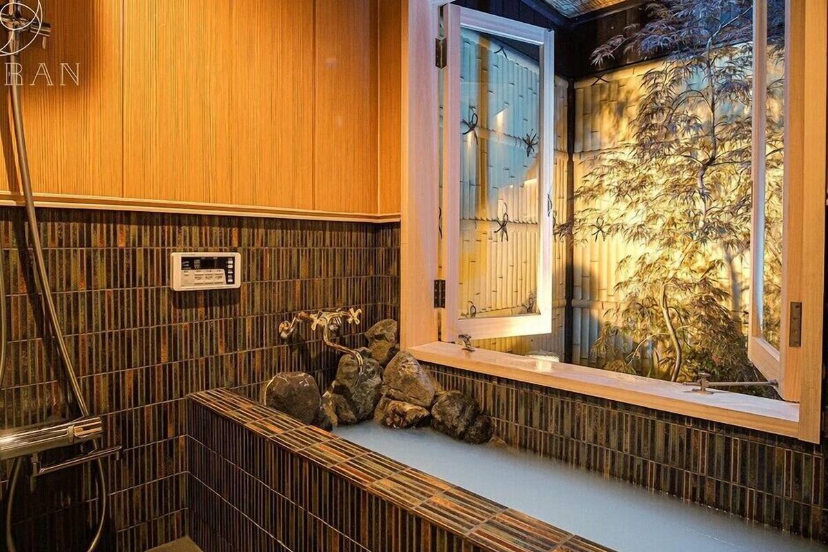 Une salle de bain avec des lambris en bois, une douche intégrée et une fenêtre donnant sur des plantes de bambou.