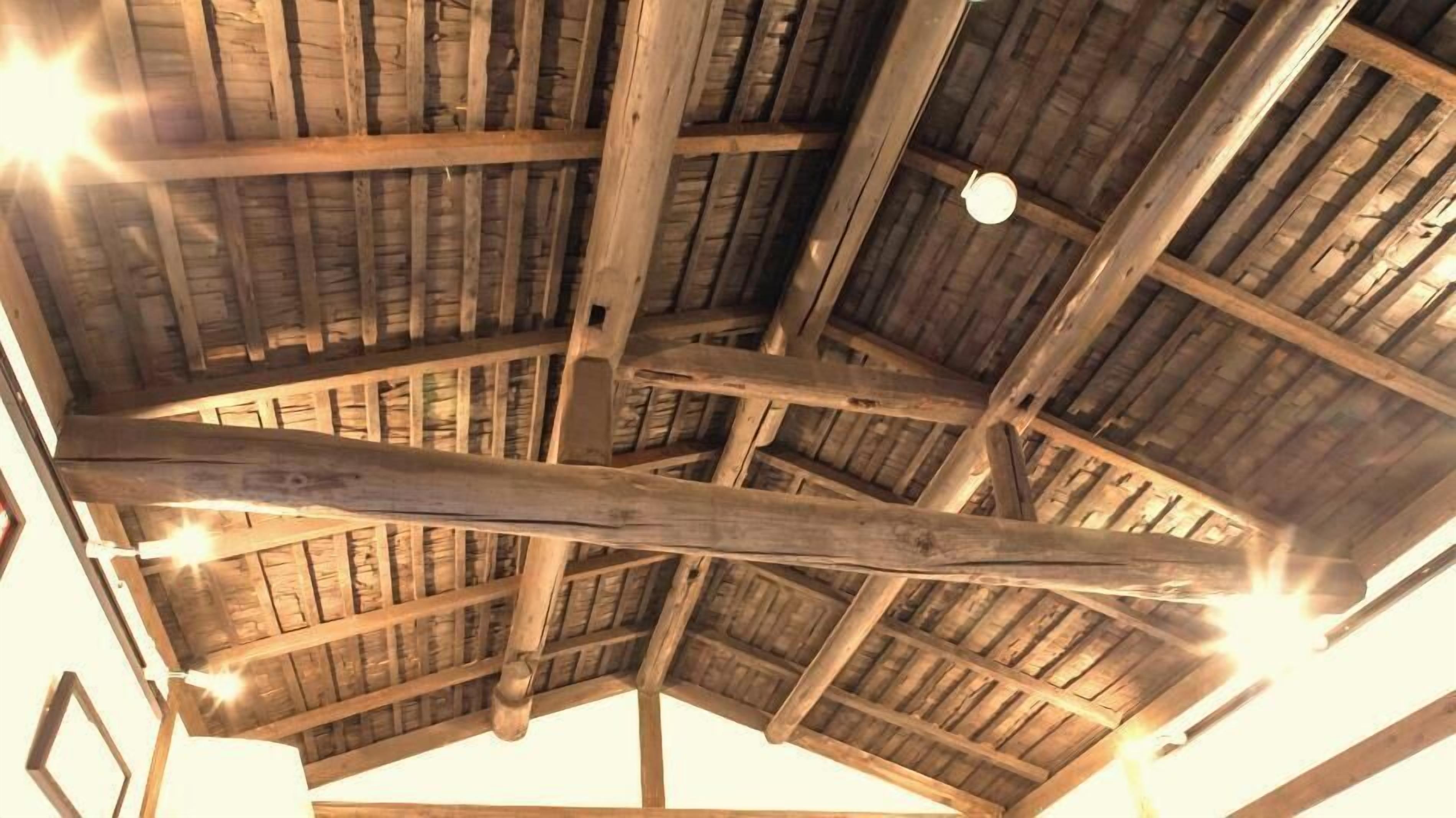 A wooden ceiling with exposed beams and a hanging light fixture.