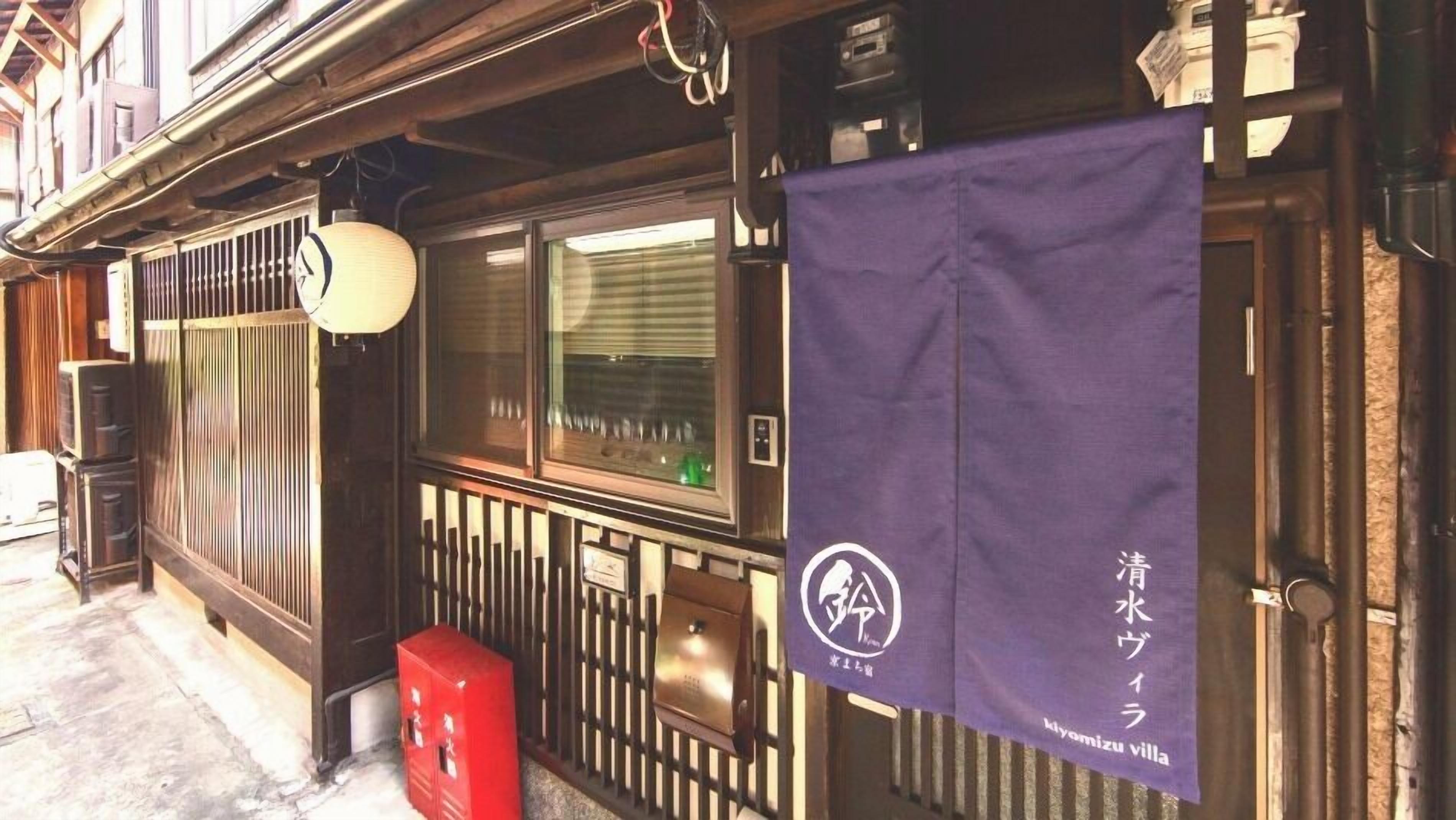 A traditional Japanese building with a wooden exterior, a sliding door, and a red mailbox.