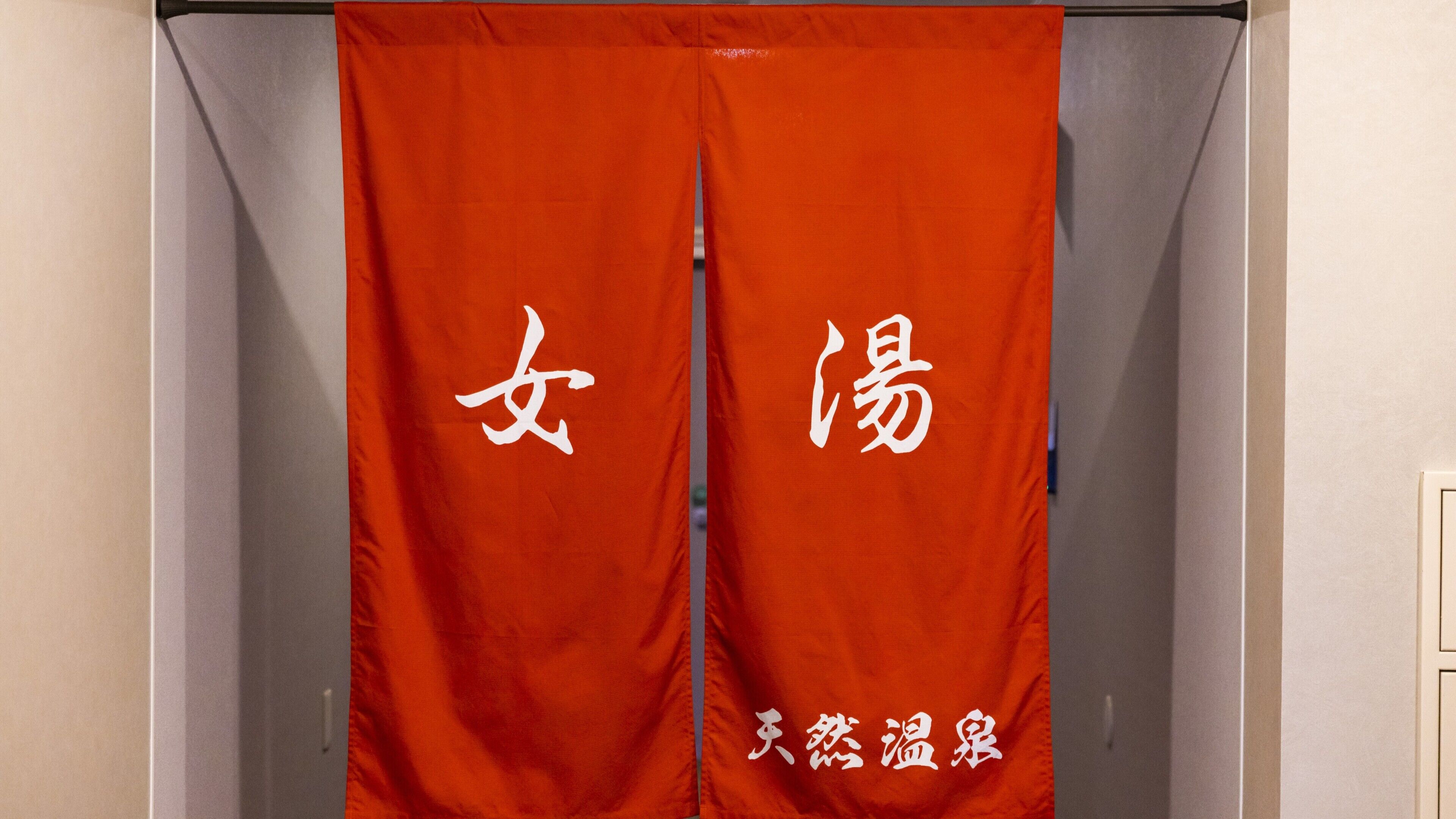 Um par de cortinas vermelhas com caracteres chineses brancos e um texto menor na parte inferior.