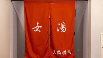 Um par de cortinas vermelhas com caracteres chineses brancos e um texto menor na parte inferior.