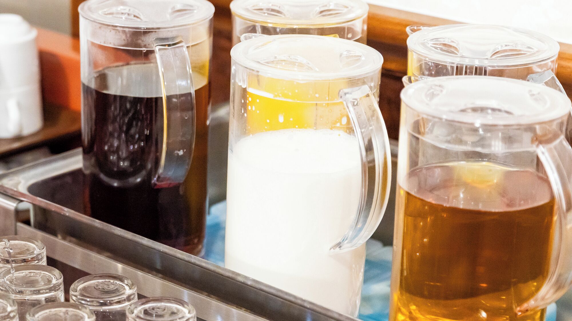 A variety of glass mugs with different colored beverages, likely a bar setting.