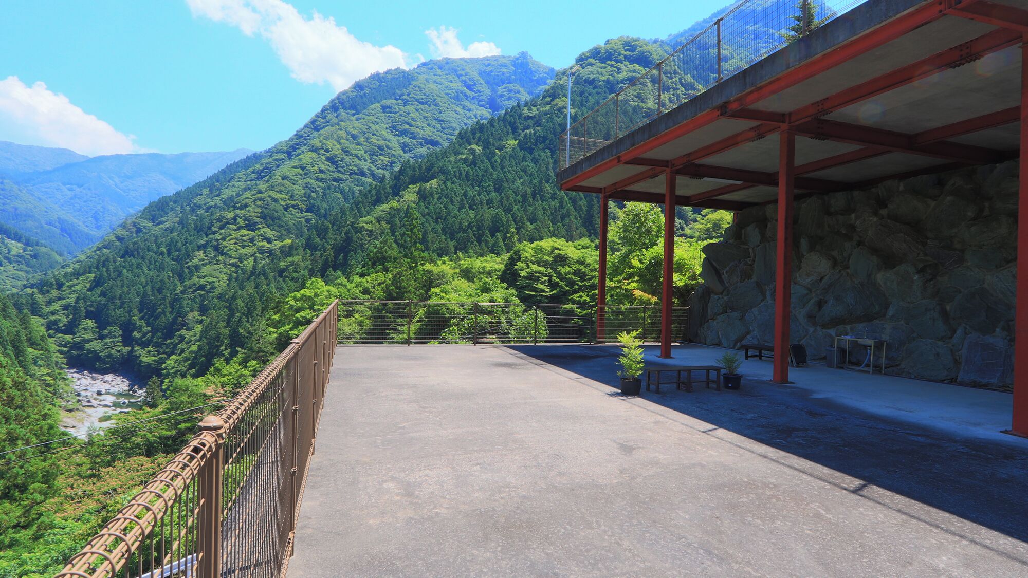 A covered outdoor area with a view of a river and mountains.