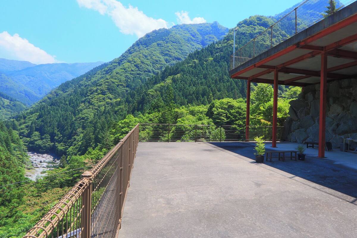 A covered outdoor area with a view of a river and mountains.
