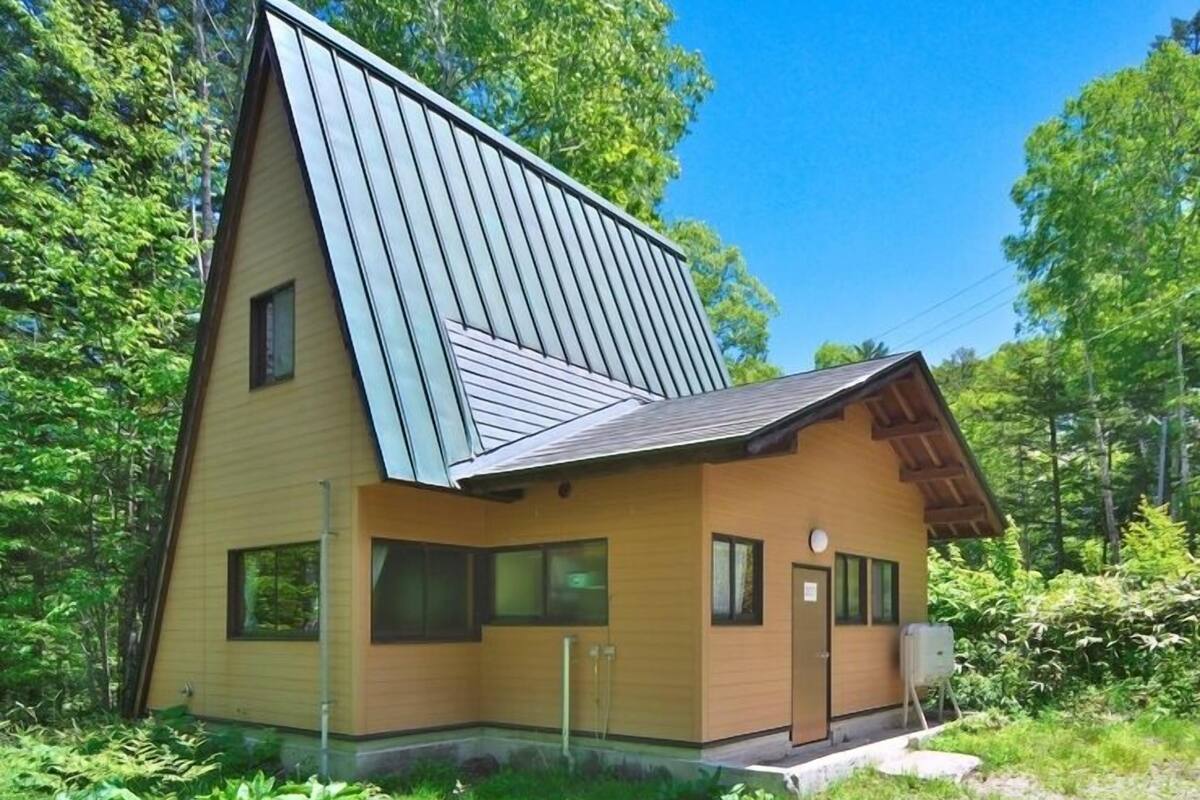 A modern house with a sloped roof, large windows, and a wooden exterior.