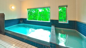 Ein Whirlpool mit Blick auf Bäume durch ein Fenster, ein gefliester Boden und eine Decke mit Holzverkleidung.