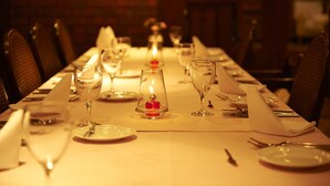 A long dining table set with plates, glasses, and cutlery, with candles and a vase in the center. - Shiki no Mori Hotel (Tateshina)