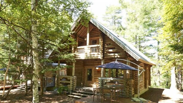 A log cabin with a balcony, outdoor seating, and a wooden deck. - Shiki no Mori Hotel (Tateshina)