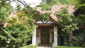 A traditional Japanese-style building with a tiled roof, stone pillars, and a wooden entrance. - Shiki no Mori Hotel (Tateshina)