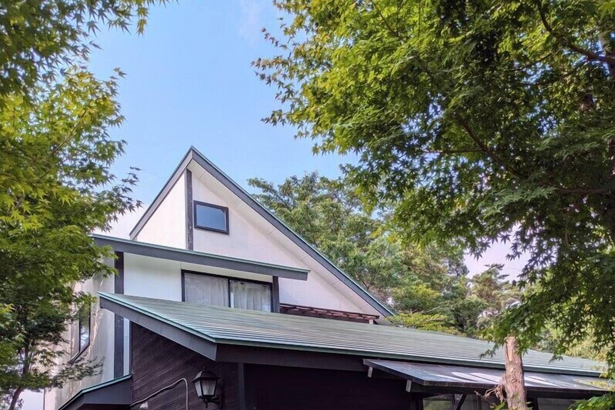 A modern two-story house with a dark exterior, a sloped roof, and a visible garage.