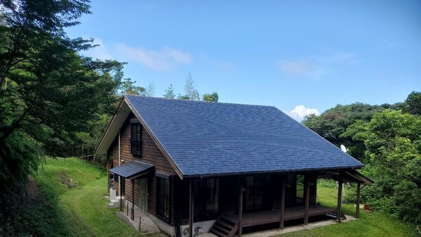 A house with a sloped roof, a covered porch, and a grassy yard.