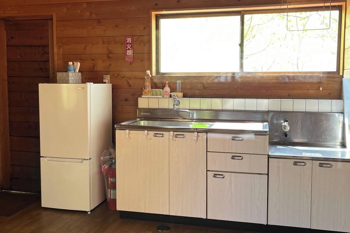 Cocina de cabaña de madera con refrigerador, pileta y ventana.