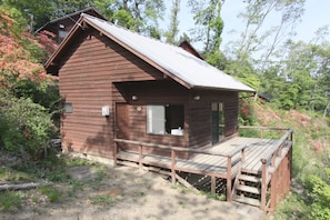 Un piccolo chalet di legno con veranda, immerso tra gli alberi.
